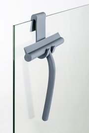 Grauer Badezimmerwischer aus Silikon, aufgehängt an einer Glasduschwand, seitliche Perspektive.