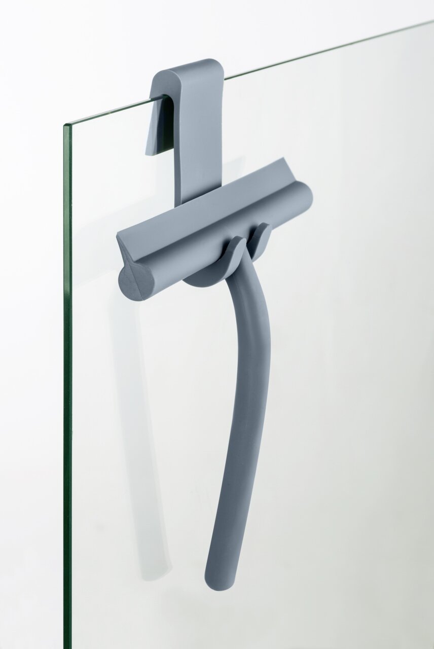 Grauer Badezimmerwischer aus Silikon, aufgehängt an einer Glasduschwand, seitliche Perspektive.