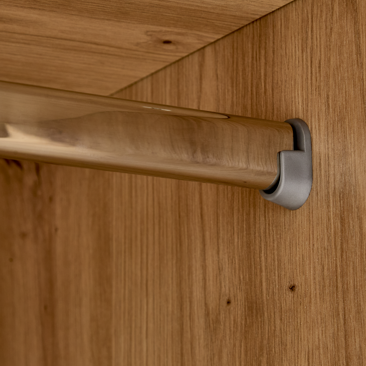 Nahaufnahme einer Kleiderstange in einem Kleiderschrank, montiert an einer Holzplatte.