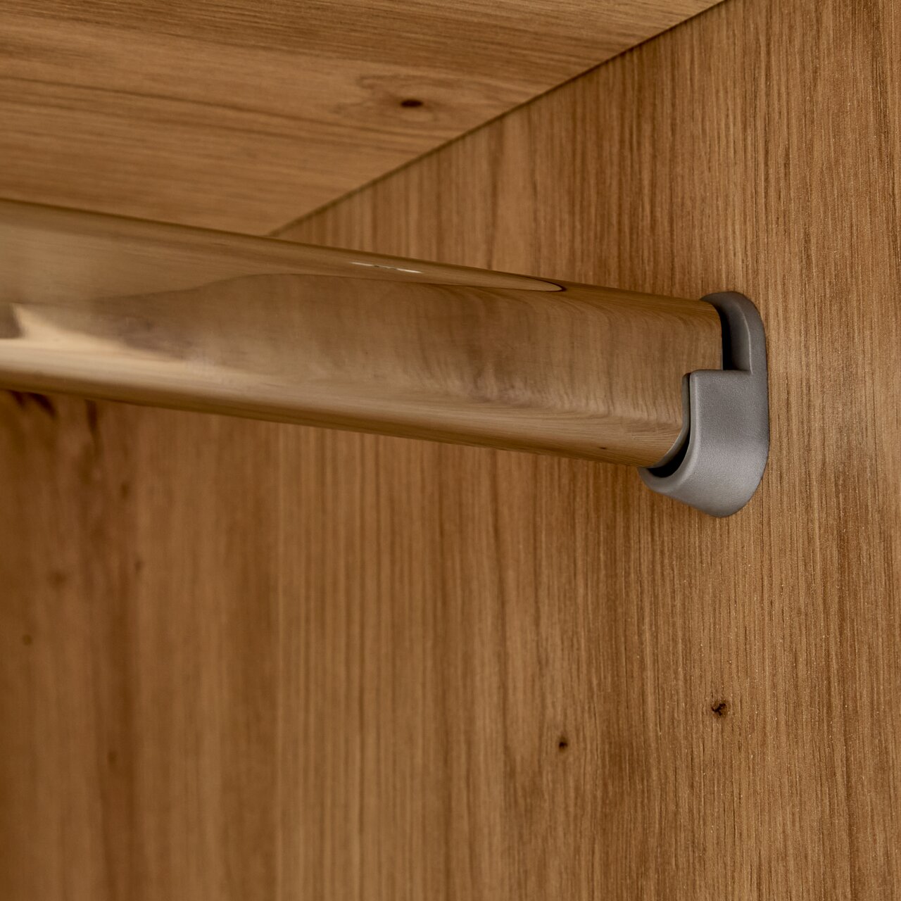 Nahaufnahme einer Kleiderstange in einem Kleiderschrank, montiert an einer Holzplatte.