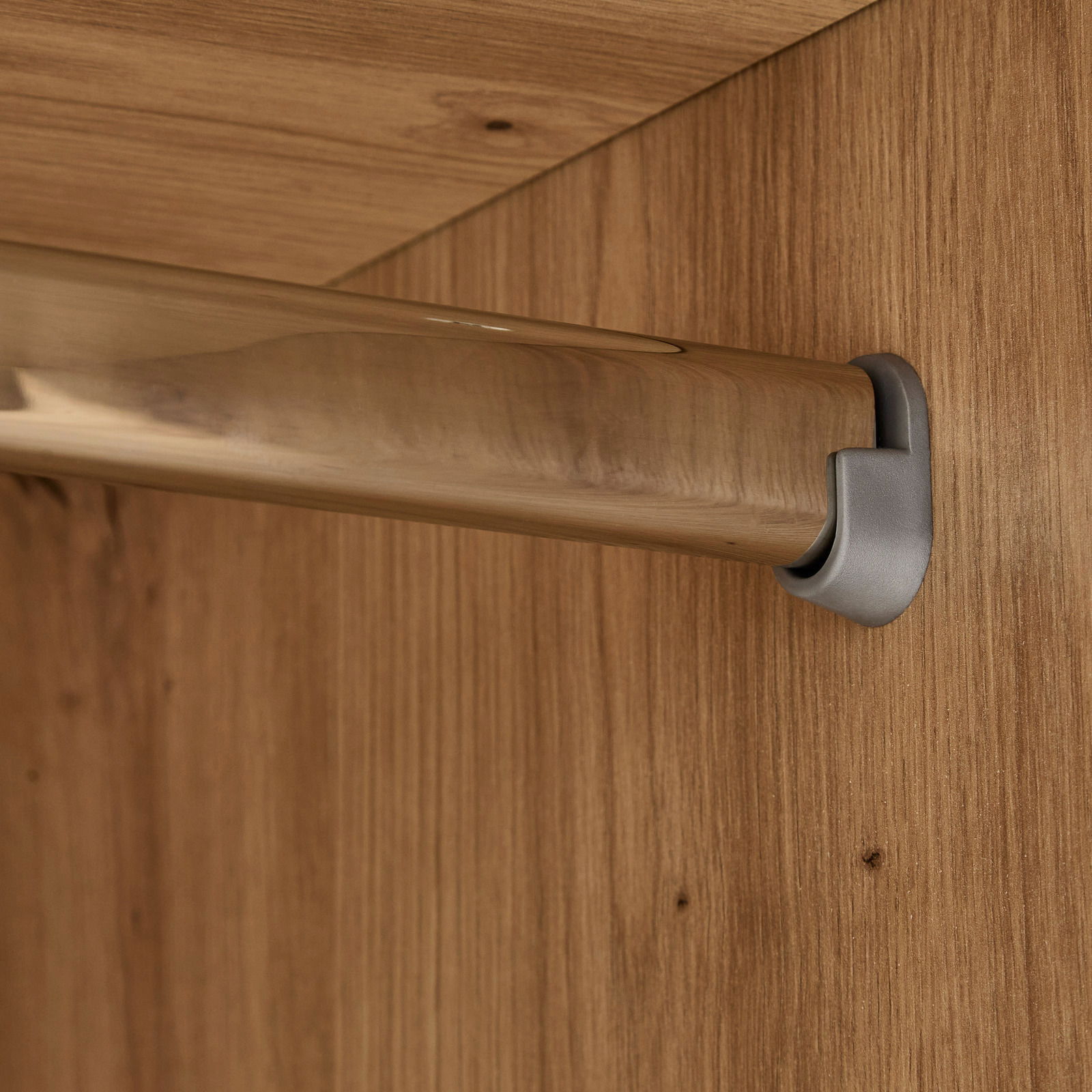 Nahaufnahme einer Kleiderstange in einem Kleiderschrank, montiert an einer Holzplatte.