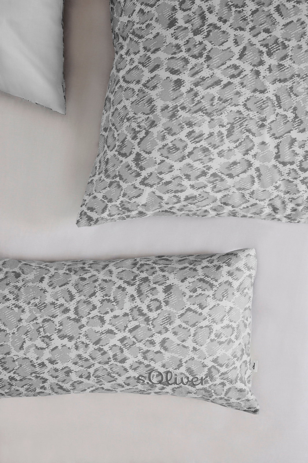 Bettwäsche-Set mit grauem Leopardenmuster, bestehend aus einem Kissenbezug und einem Deckenbezug, aus der Vogelperspektive fotografiert.