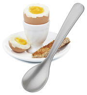 Silberner Eierlöffel in Nahaufnahme neben einem weichgekochten Ei im Eierbecher auf einem Teller mit Toaststreifen.