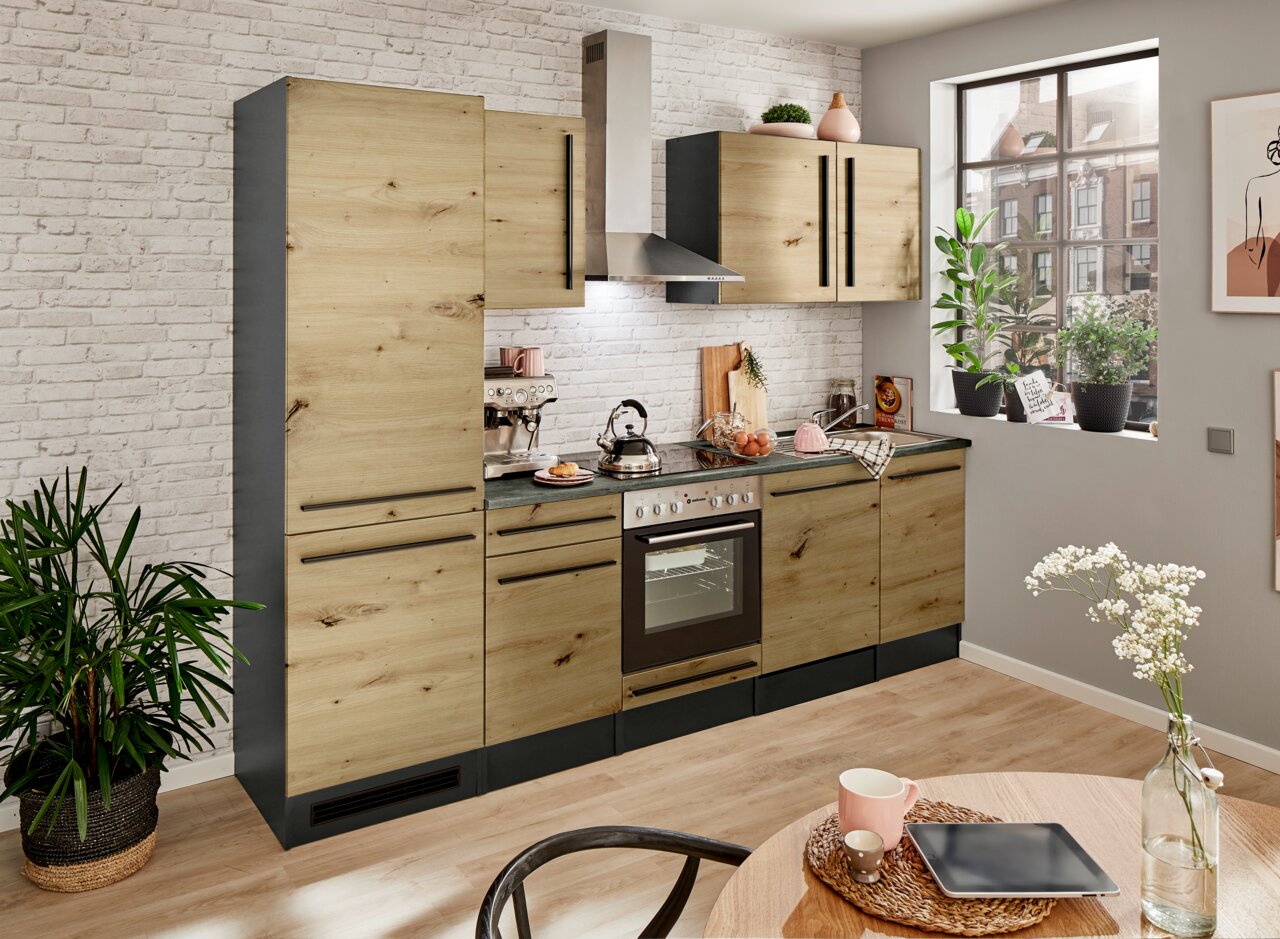 Moderne Küchenzeile in Holzoptik mit schwarzen Griffen, bestehend aus Hochschrank, Hängeschränken, Herd und Spüle, in einem hellen Raum mit großen Fenstern und Pflanzen, seitliche Perspektive.
