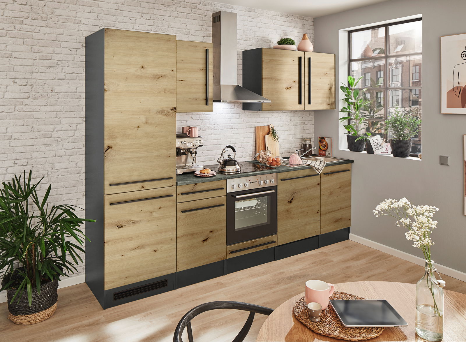 Moderne Küchenzeile in Holzoptik mit schwarzen Griffen, bestehend aus Hochschrank, Hängeschränken, Herd und Spüle, in einem hellen Raum mit großen Fenstern und Pflanzen, seitliche Perspektive.
