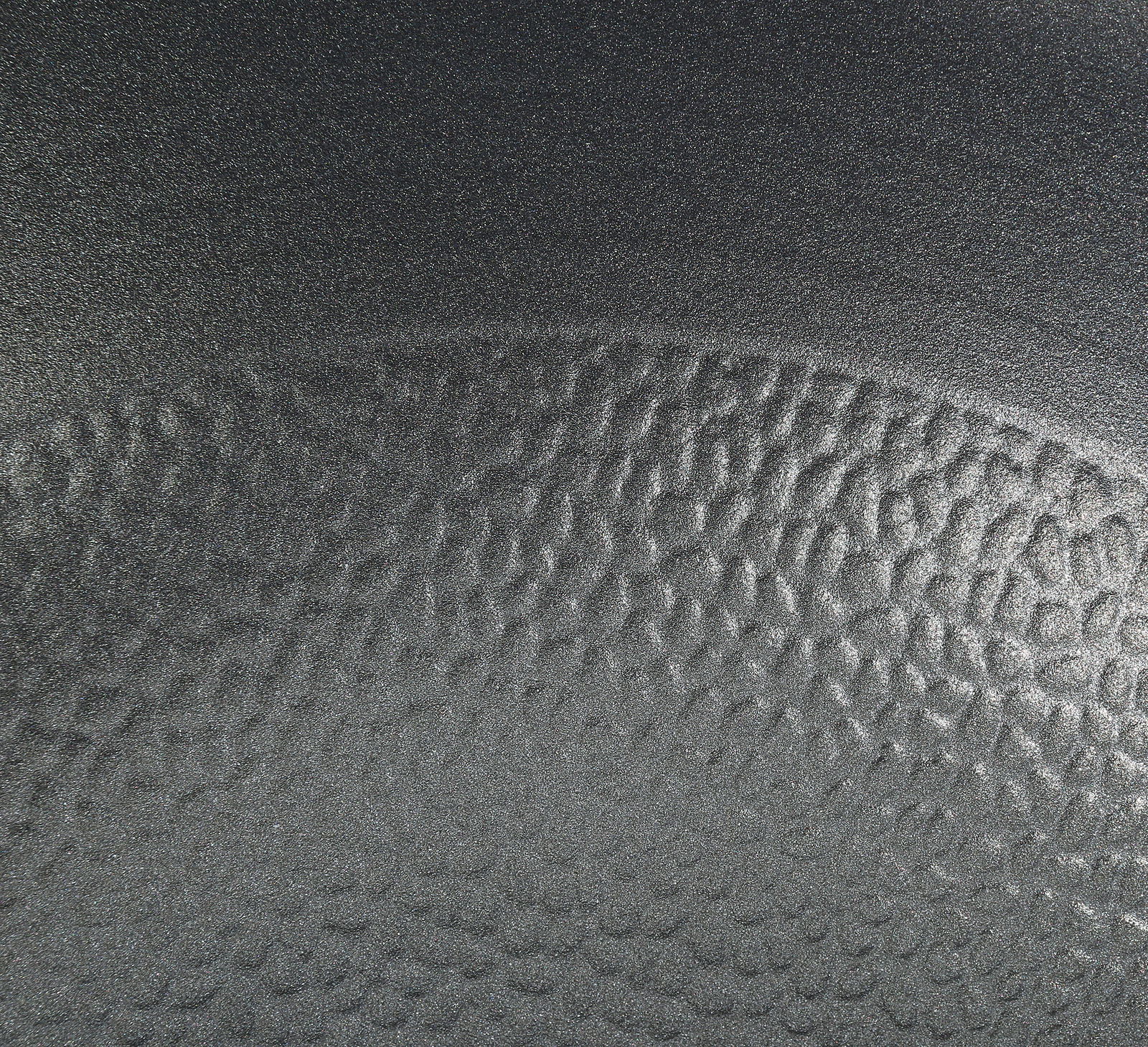 Nahaufnahme der strukturierten Oberfläche einer Wokpfanne COUNTRY, 28 cm, in schwarzer Farbe.