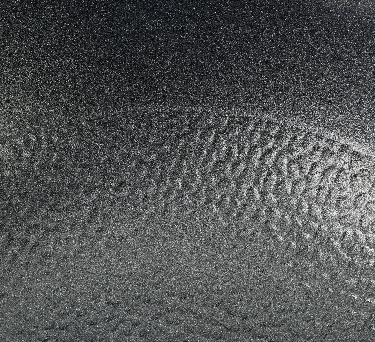 Nahaufnahme der strukturierten Oberfläche einer Wokpfanne COUNTRY, 28 cm, in schwarzer Farbe.
