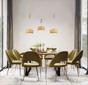 Moderne Pendelleuchte über einem stilvoll gedeckten Esstisch mit grünen Stühlen, seitliche Perspektive.