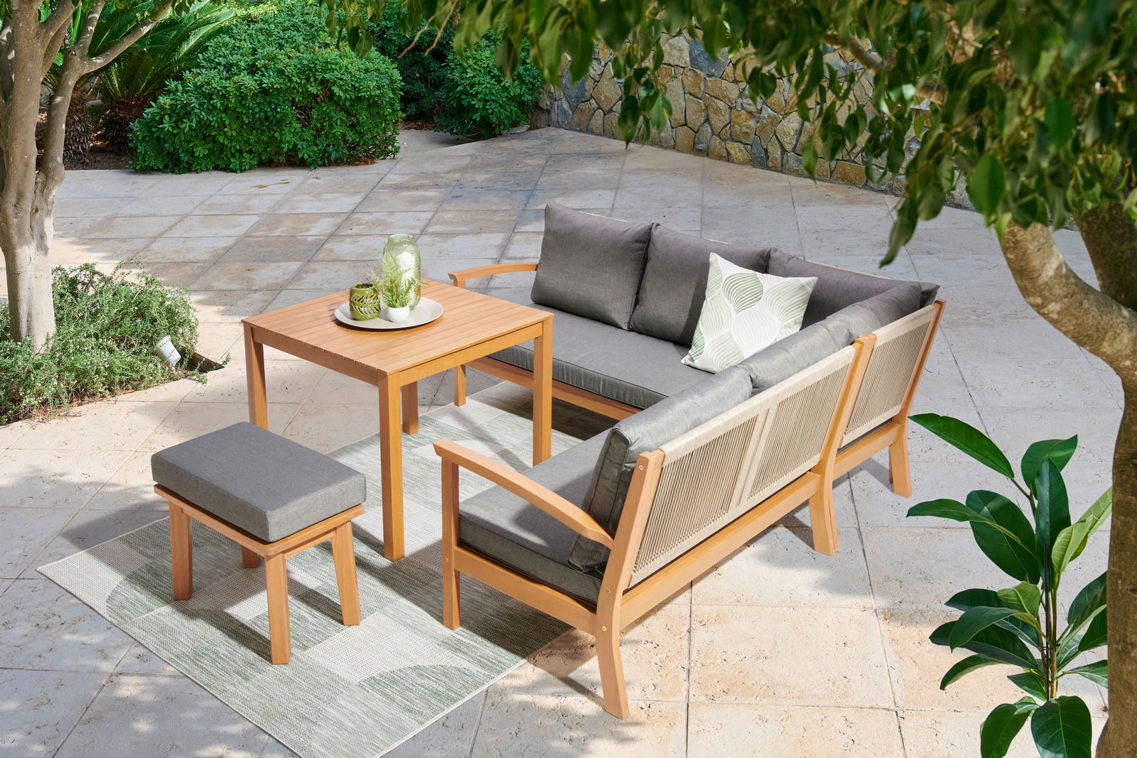 Gartenhocker aus Holz mit grauem Polster, Teil einer stilvollen Gartensitzgruppe, von oben fotografiert.