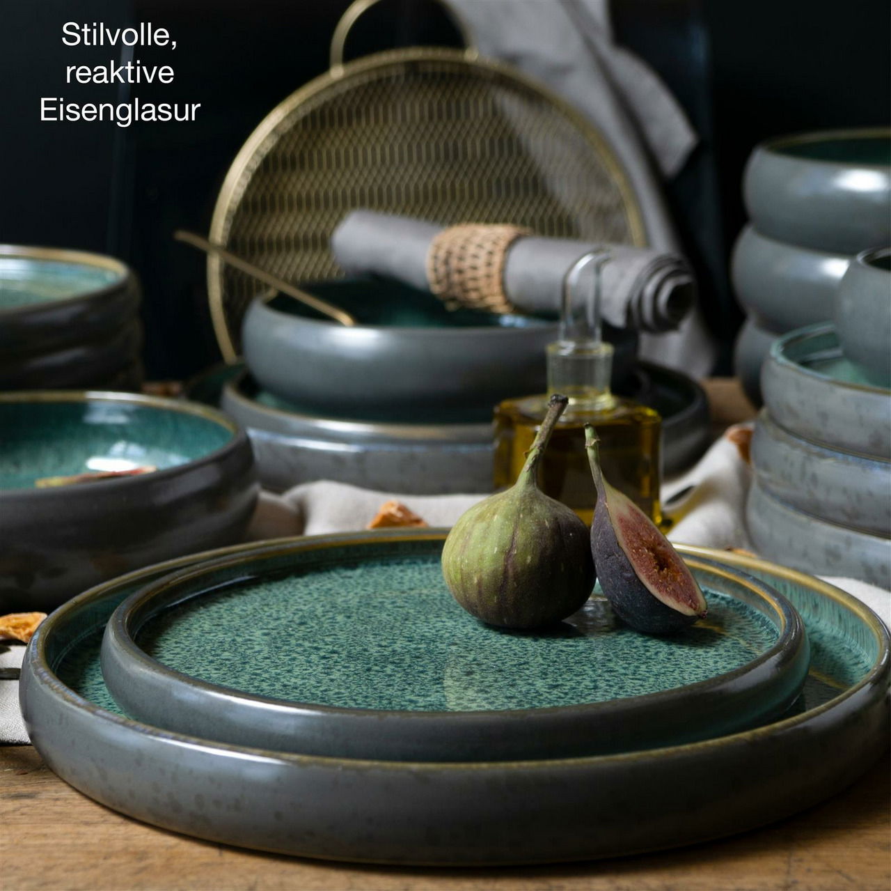 Perspektive: Nahaufnahme eines stilvollen, reaktiven Tafelservices mit grüner Eisenglasur, dekoriert mit frischen Feigen.