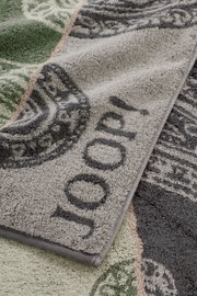 Detailaufnahme eines flauschigen Frottee-Handtuchs mit floraler Musterung in Grau und Grün, schräg von oben fotografiert