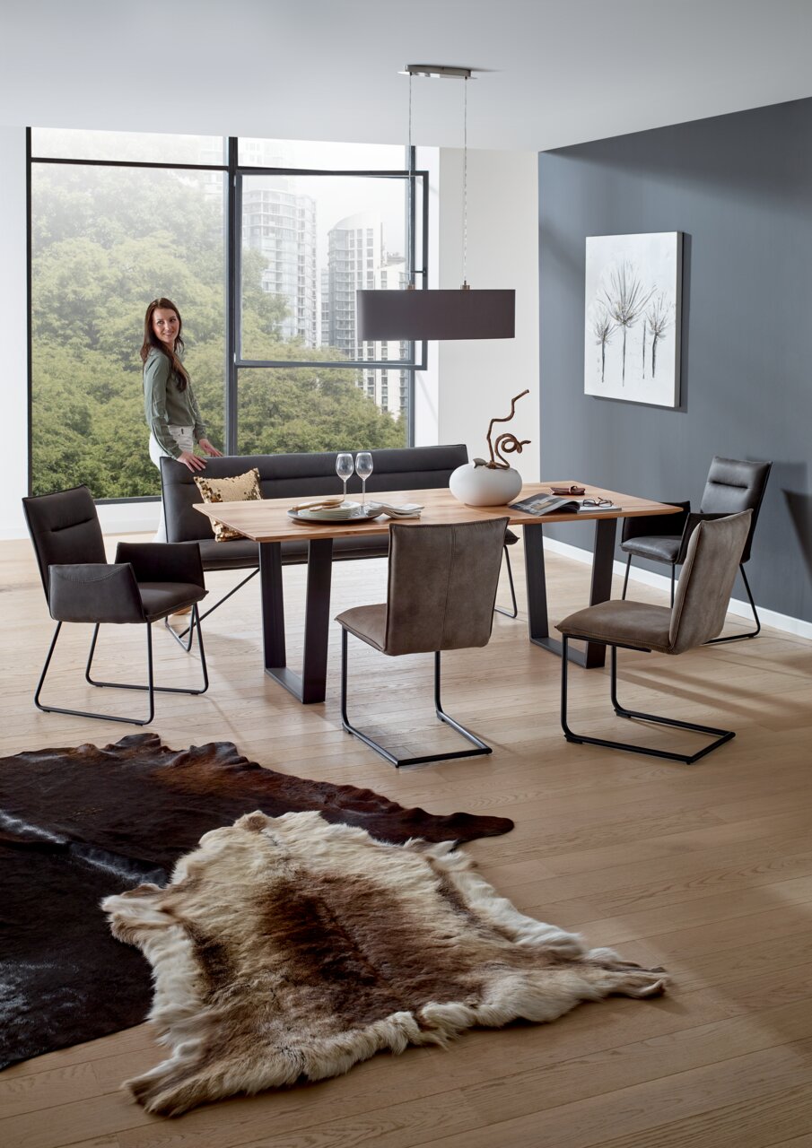 Valnatura Stoel SCALA Een moderne eetkamer met een houten tafel en zweefstoelen, gezien vanuit de zijkant.