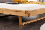 Nahaufnahme eines Balkenbetts aus Holz mit sichtbarer Eckverbindung und stabilen Beinen, seitliche Perspektive.