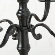 Nahaufnahme eines schwarzen, runden Kerzenleuchters mit geschwungenen Armen und elegantem Design.