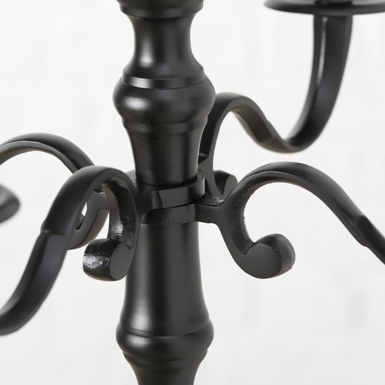 Nahaufnahme eines schwarzen, runden Kerzenleuchters mit geschwungenen Armen und elegantem Design.