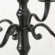 Nahaufnahme eines schwarzen, runden Kerzenleuchters mit geschwungenen Armen und elegantem Design.