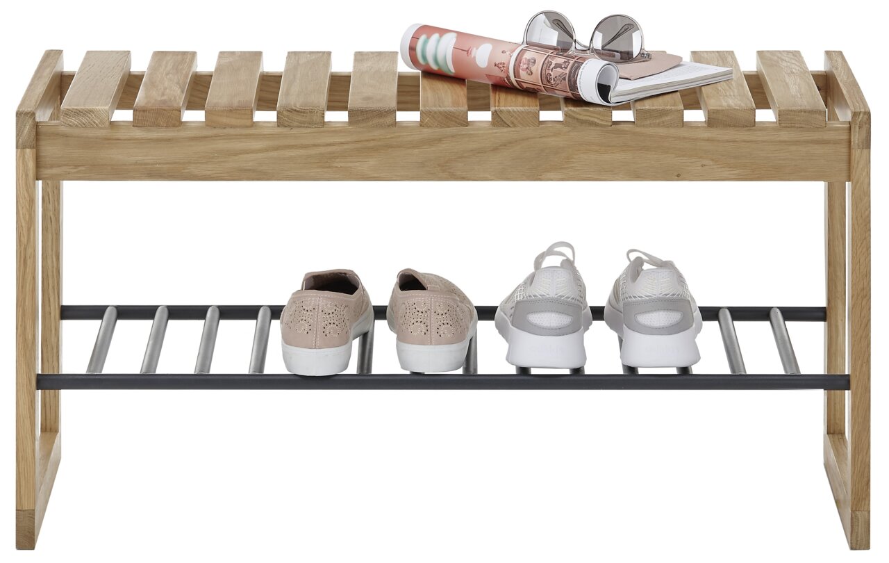 Garderobenbank aus Holz mit Metallablage, frontal fotografiert. Auf der Bank liegen Zeitschriften und eine Brille, darunter stehen Schuhe.