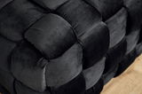 Nahaufnahme eines schwarzen, gepolsterten Hockers mit geflochtenem Design, seitliche Perspektive.