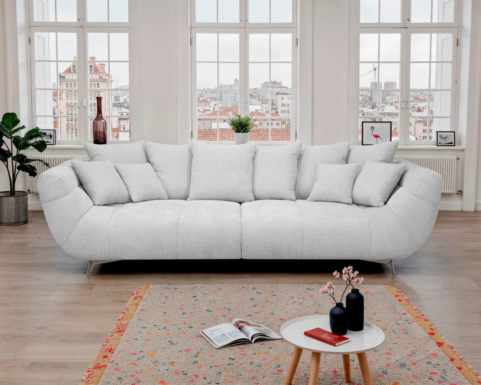 Hellgraues, gepolstertes 3-Sitzer-Designer-Sofa mit mehreren Kissen und schmalen Metallfüßen in modernem Wohnzimmer Frontansicht.