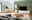 Modernes Wohnzimmer mit Sideboard in heller Holzoptik, frontal betrachtet. Das Sideboard steht links im Raum, dekoriert mit Pflanzen und Büchern.