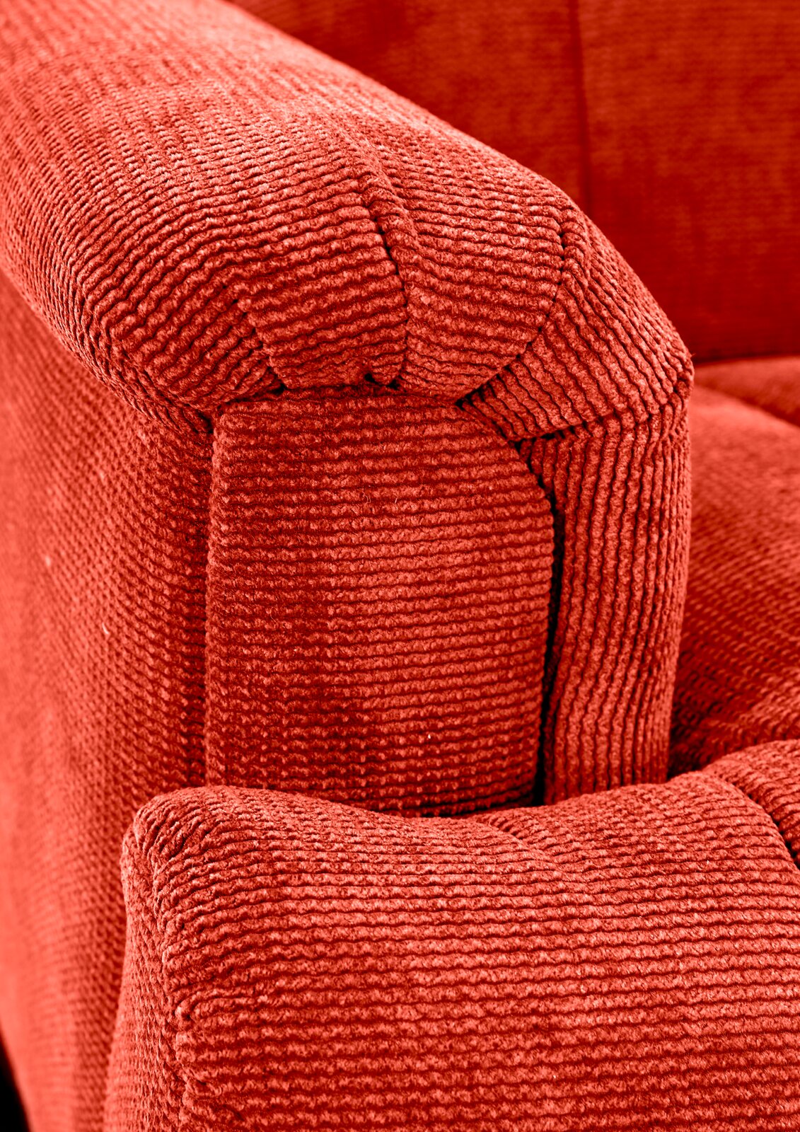 Close-up van een rode, gestructureerde bekleding van een tweezitsbank, met de nadruk op de armleuning.