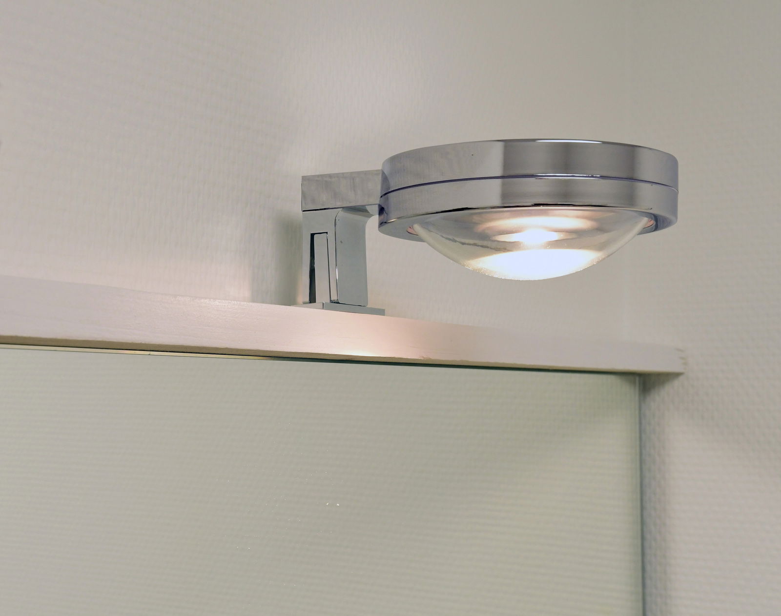 LED Bad- und Spiegelklemmleuchte in seitlicher Perspektive, montiert über einem Spiegel mit modernem, chromfarbenem Design.