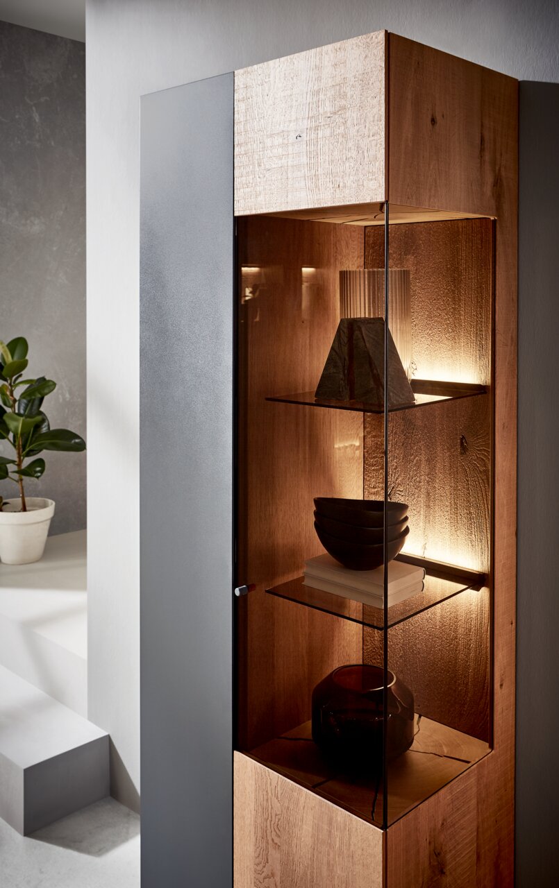 Moderne wandcombinatie Valnatura LOVIS van hout en glas, zijaanzicht met decoratieve verlichting en planken.
