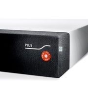 Ecke einer Viscomatratze mit grauem Bezug und Aufschrift 'PLUS' sowie 'FIRM' Siegel, seitliche Perspektive