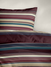 Bettwäsche mit Streifenmuster in Rot-, Blau- und Beigetönen, perspektivisch von oben fotografiert