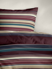 Bettwäsche mit Streifenmuster in Rot-, Blau- und Beigetönen, perspektivisch von oben fotografiert