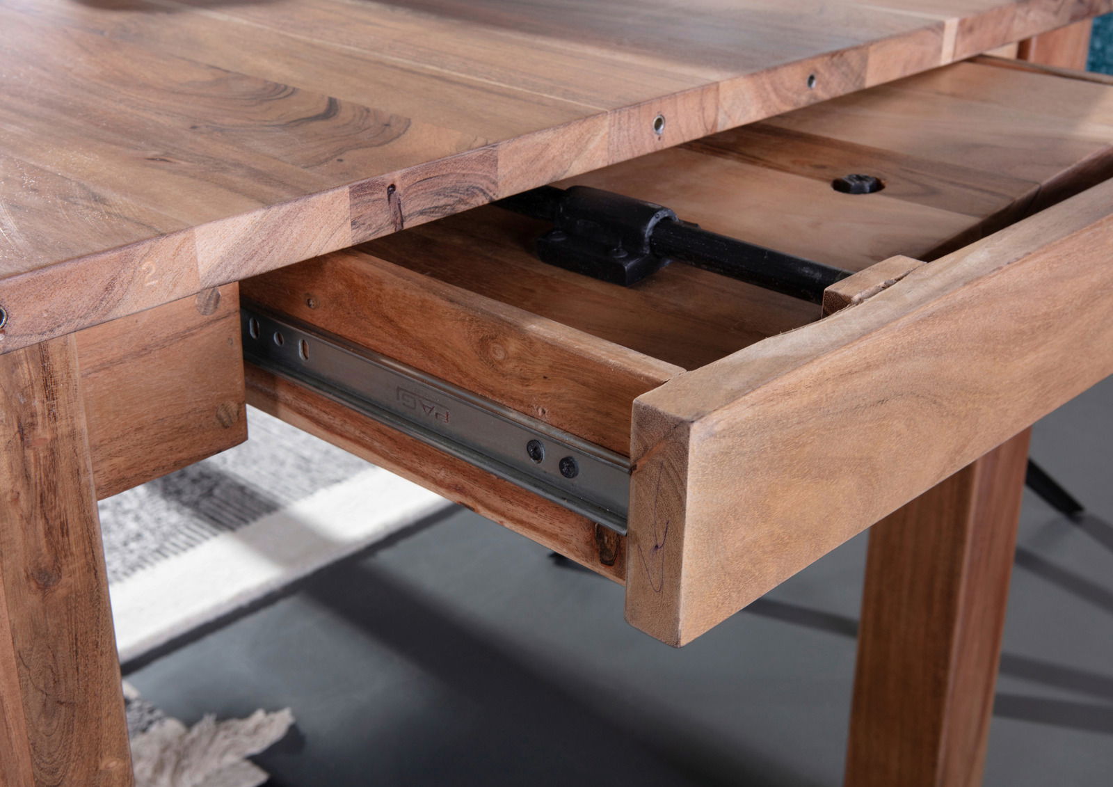 Nahaufnahme eines Esstisches aus Holz mit ausgezogenem Schubfach, seitliche Perspektive