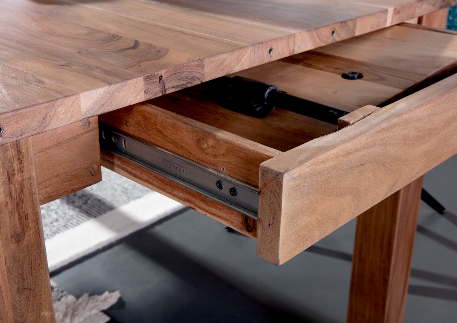 Nahaufnahme eines Esstisches aus Holz mit ausgezogenem Schubfach, seitliche Perspektive