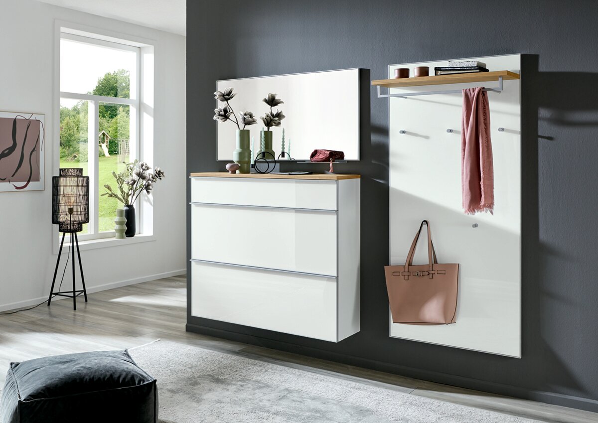 Modernes Flur-Set in Weiß mit Holzablage: links eine Kommode mit drei Schubladen und großem Spiegel, rechts eine Wandgarderobe mit Ablage, Haken und hängender Tasche; Perspektive: frontale, leicht seitliche Raumansicht.