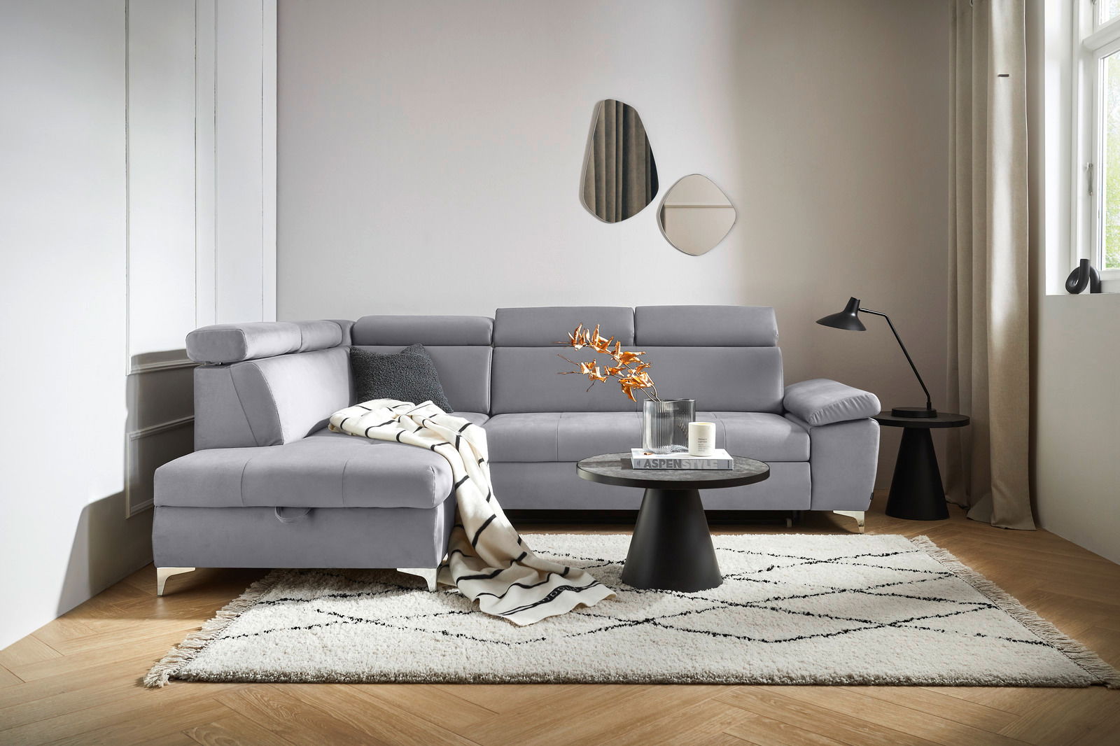 Graue Rundecke (L) in einem modernen Wohnzimmer, von vorne betrachtet, mit einem Beistelltisch und Dekorationen.