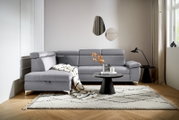 Graue Rundecke (L) in einem modernen Wohnzimmer, von vorne betrachtet, mit einem Beistelltisch und Dekorationen.