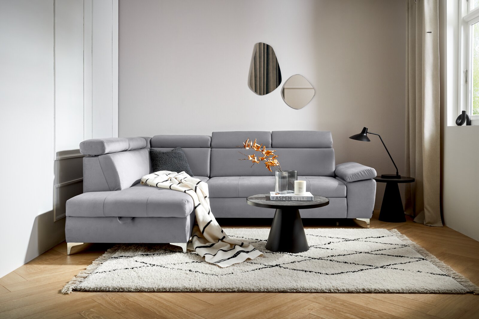 Grijze hoekbank (L) in een moderne woonkamer, gezien vanaf de voorkant, met een bijzettafeltje en decoraties.