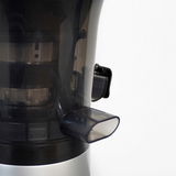 Nahaufnahme eines Slow Juicers mit seitlichem Auslass und transparentem Gehäuse.
