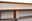 Nahaufnahme eines Holzfußes eines Sideboards mit verstellbarem Kunststofffuß auf Teppichboden.