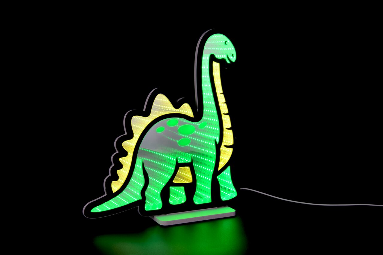 Grün leuchtende LED-Dekolampe in Dinosaurierform (Langhals) mit gelben Akzenten, auf einem Sockel mit Stromkabel, schräg von vorn rechts vor schwarzem Hintergrund