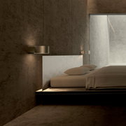 Moderne Wandleuchte PURE Clipse in einem minimalistischen Schlafzimmer, seitliche Perspektive.