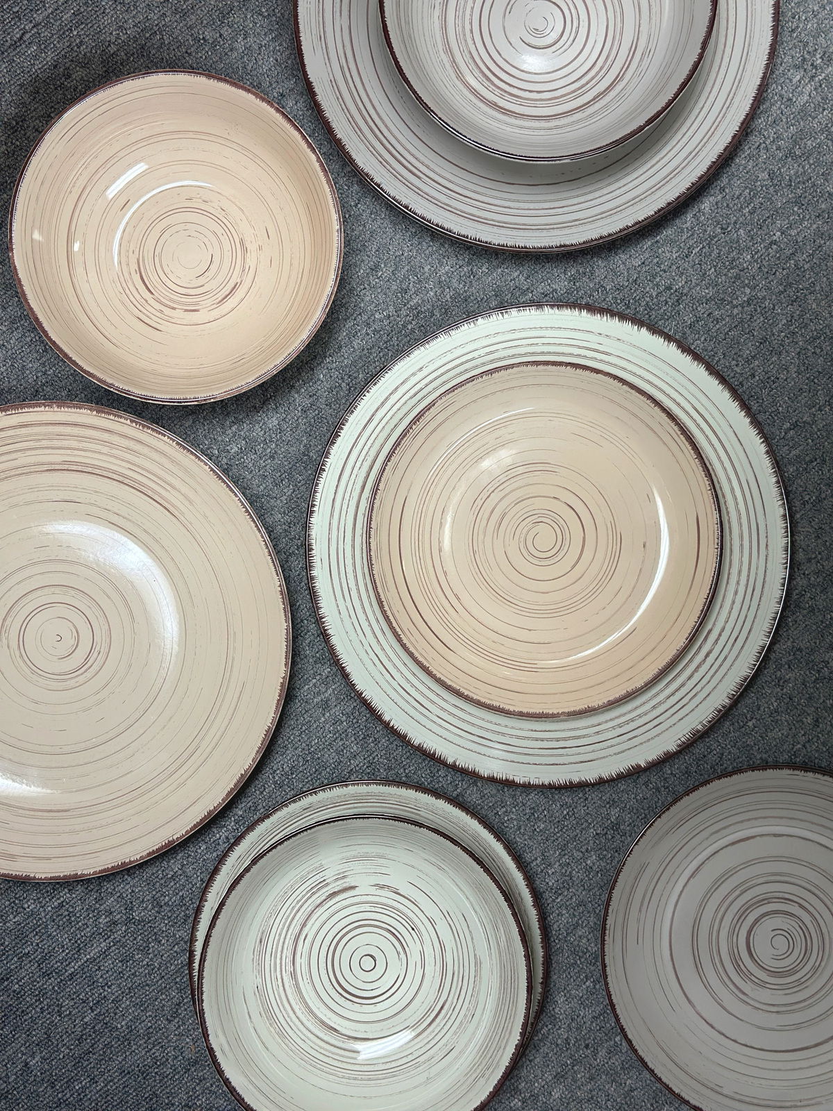 Vogelperspektive auf ein 24-teiliges Kombiservice mit kreisförmigem Muster in Beige- und Brauntönen.