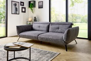 Graues Megasofa in einem modernen Wohnzimmer mit großen Fenstern, seitliche Perspektive
