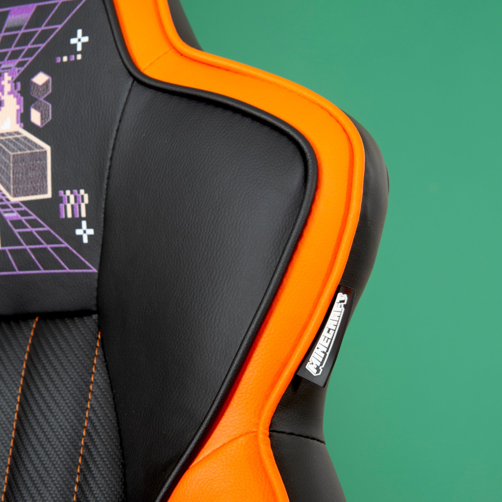 Detailfoto van een gamingstoel met een zwart-oranje ontwerp, grafische patronen en een merklogo.