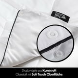 Nahaufnahme einer weißen Bettdecke mit Druckknöpfen aus Kunststoff und Soft Touch Oberfläche, perspektivisch von oben fotografiert.