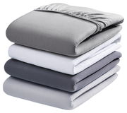 Ein Stapel von vier Spannbetttüchern in verschiedenen Grautönen und Weiß, von der Seite betrachtet.