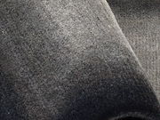 Nahaufnahme eines grauen Wollteppichs mit weicher Textur, von oben betrachtet.