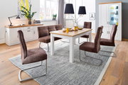 Modernes Esszimmer-Set mit weißem Holztisch und Holzoptik-Platte, brauner Polsterbank und vier braunen Schwingstühlen auf grauem Teppich, fotografiert in leicht erhöhter Frontalansicht.