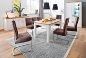 Moderne eetkamerset met een witte houten tafel en een blad in houtlook, een bruine gestoffeerde bank en vier bruine schommelstoelen op een grijs tapijt, gefotografeerd in een licht verhoogd vooraanzicht.