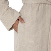 Nahaufnahme eines beigen Kapuzenbademantels in Größe XL mit einer Hand in der Tasche, seitliche Perspektive.