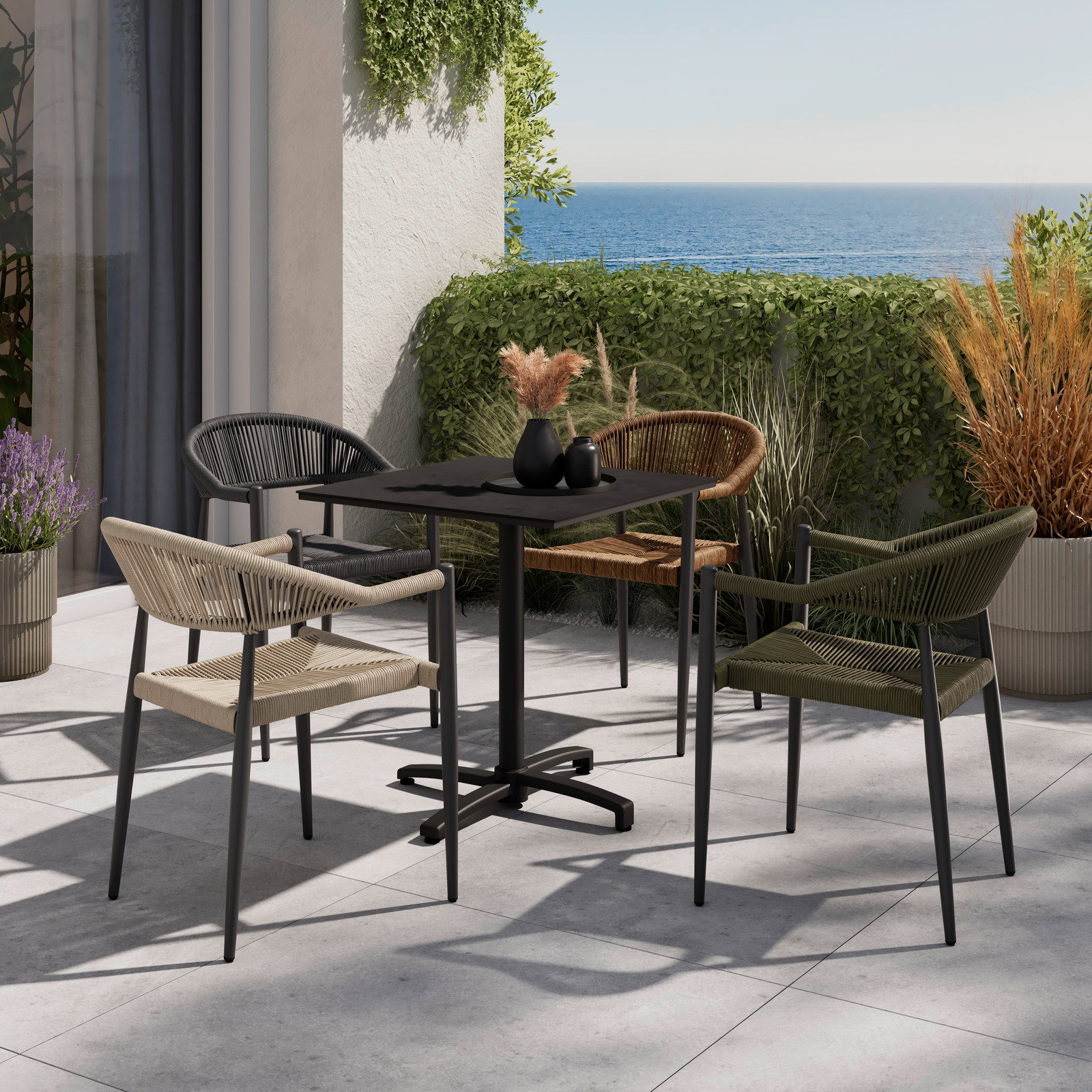 Vier stilvolle Stapelsessel in verschiedenen Farben um einen modernen Tisch auf einer Terrasse mit Meerblick, aus seitlicher Perspektive.